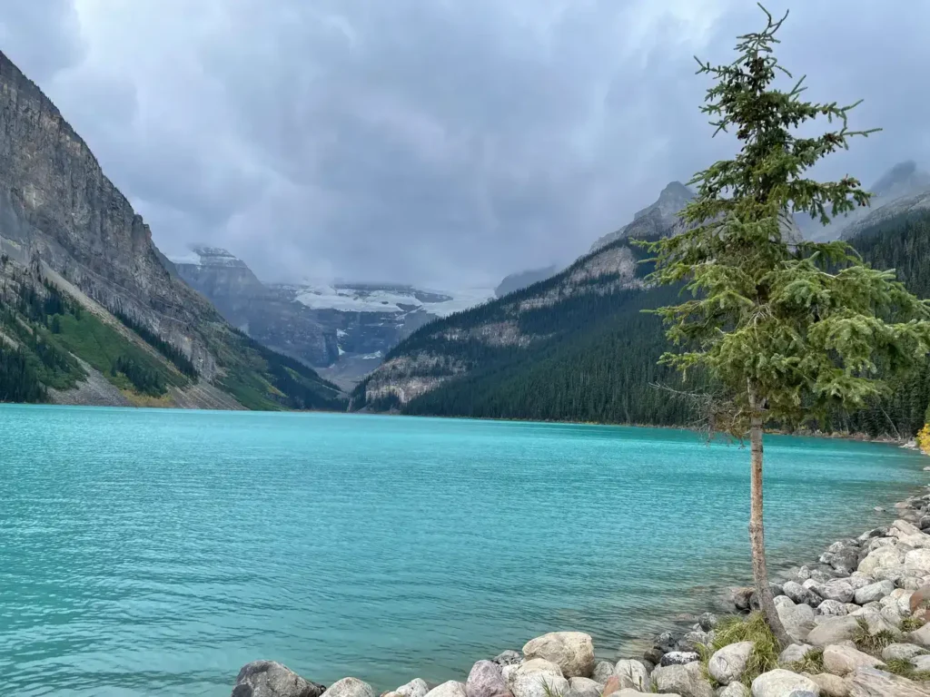 Le Lac Louise avec sa couleur turquoise et ses montagnes en arrière plan sous un temps nuageux