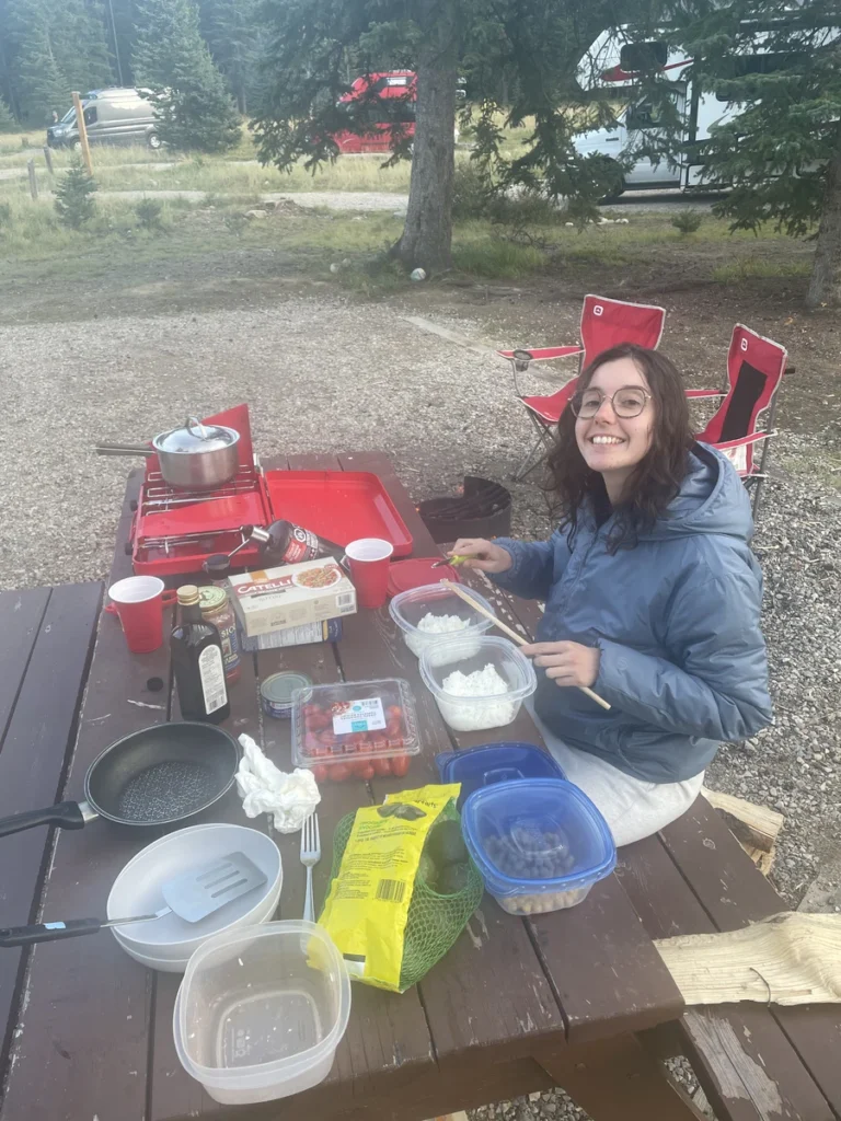 Gwen préparant des salades sur une table de camping