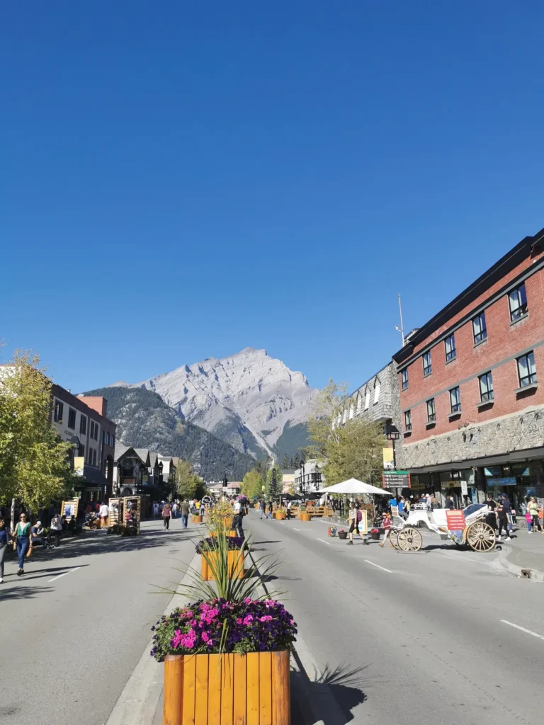 Rue principale de Banff avec en fond les montagnes sous un ciel parfaitement bleu