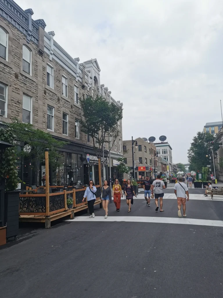 Rue piétonne avec des personnes marchant à côté d'une terrasse sous un temps nuageux