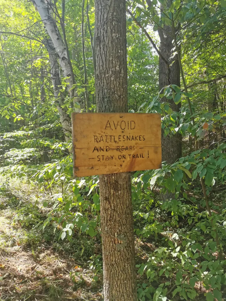 panneau d'avertissement indiquant qu'on peut croiser des serpents ou des ours si nous nous éloignons du sentier