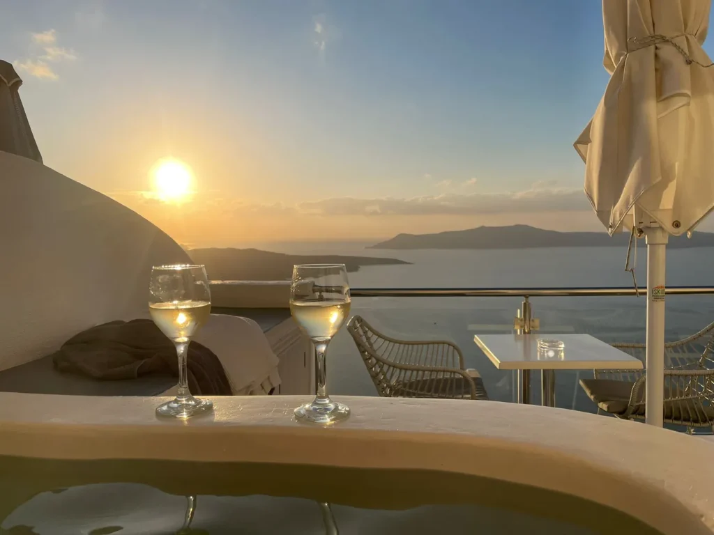 2 verres de champagne posés sur le bord du jacuzzi avec le coucher de soleil en arrière plan