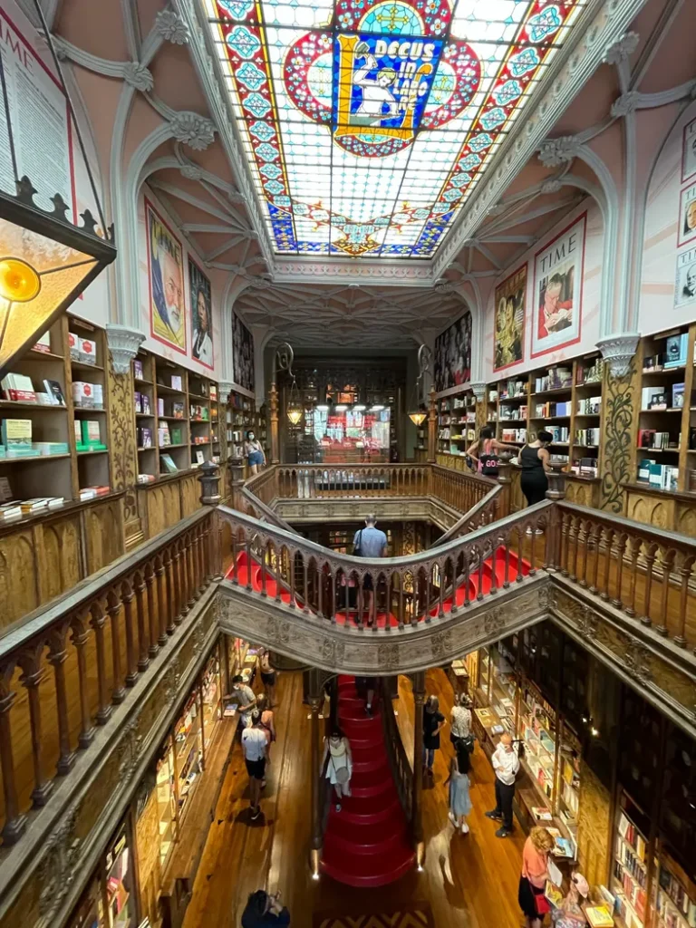 Intérieur de la Livraria Lello. Un grand escalier en bois au milieu avec une verrière au plafond