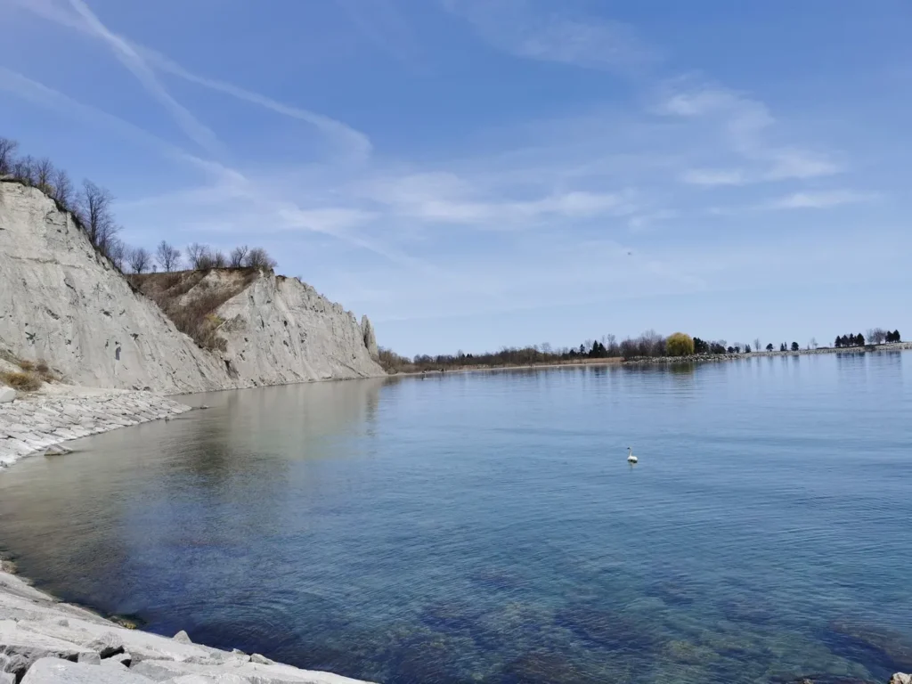 Une côte rocheuse avec des falaises surplombant une étendue d'eau calme et scintillante.