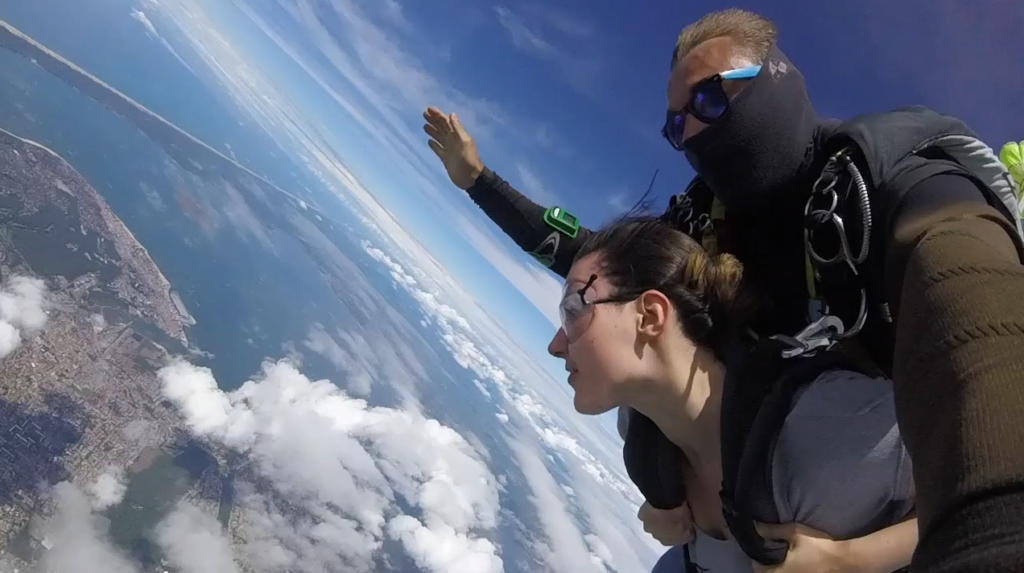 Un homme et une femme en tandem, sautant en parachute dans un ciel ensoleillé, vivant une expérience inoubliable.