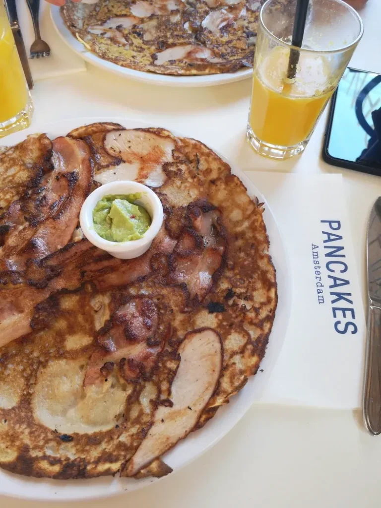 Une table avec une assiette de pancakes dorés et un verre de jus d'orange frais.