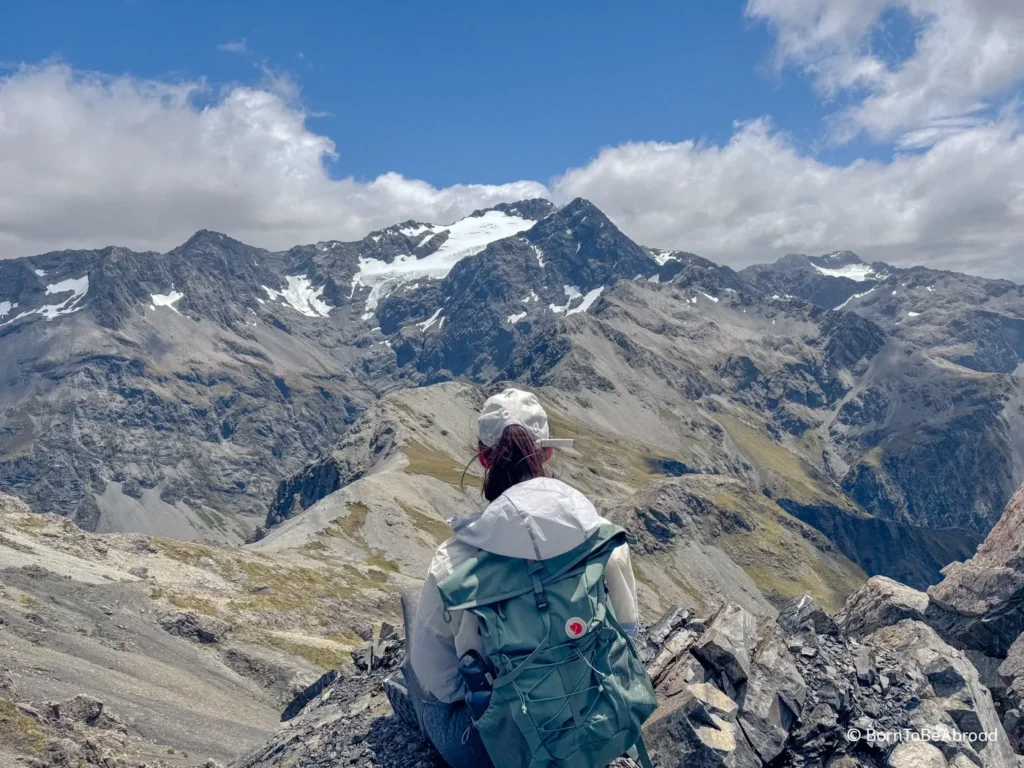 Gwen se tenant assise en face de montagnes enneigées, l'un de mes moments préférés durant mon itinéraire de mon road trip dans l'île du sud de la Nouvelle-Zélande