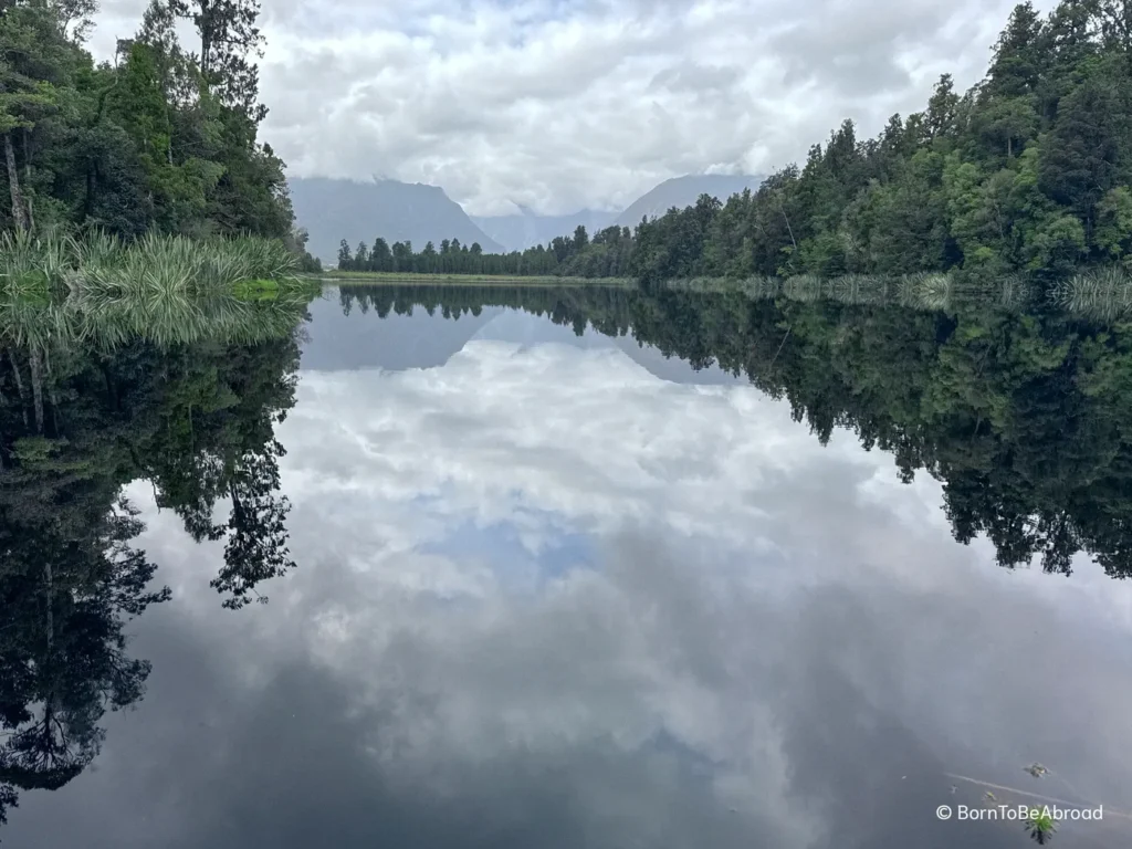 Réflection parfaite d'une forêt sur un lac calme. Le temps est très nuagueux.