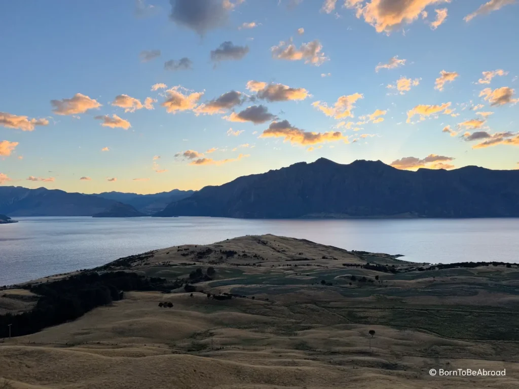 Soleil se levant derrière une montagne avec un lac en premier plan