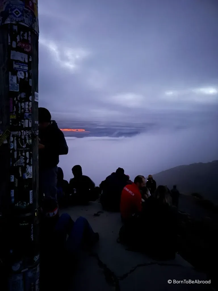 De nombreuses personnes assises attentent le lever du soleil au sommet du Roy's Peak