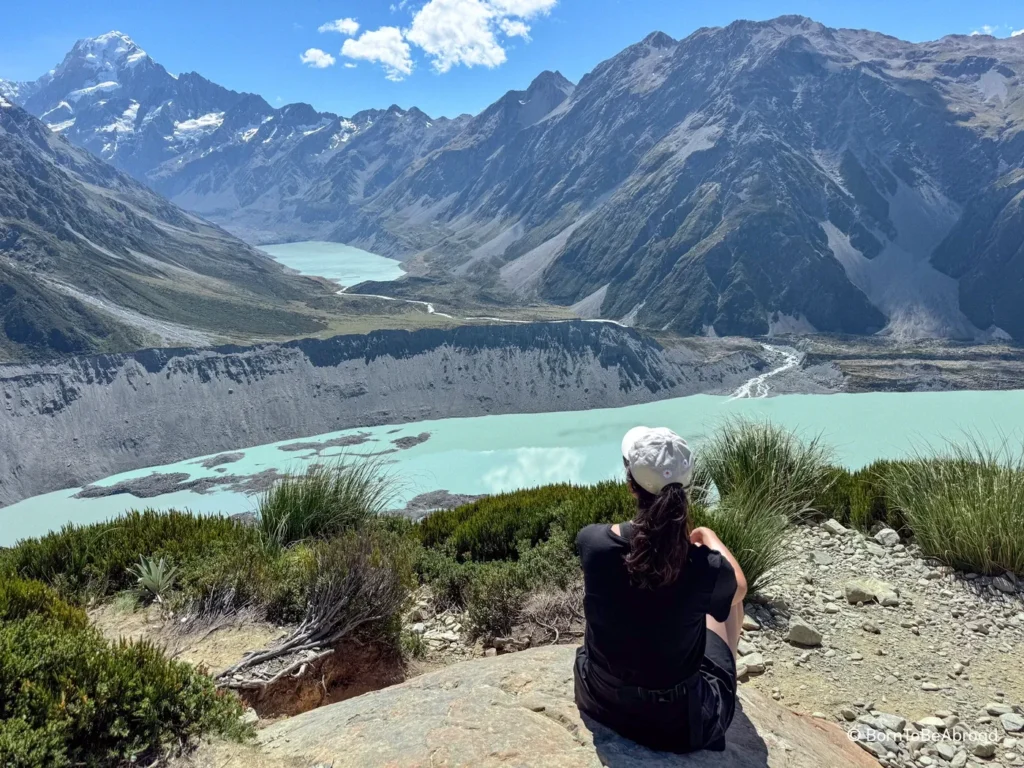 Gwen contemplant un glacier à la couleur turquoise au pied du Mont Cook sous un temps ensoleillé