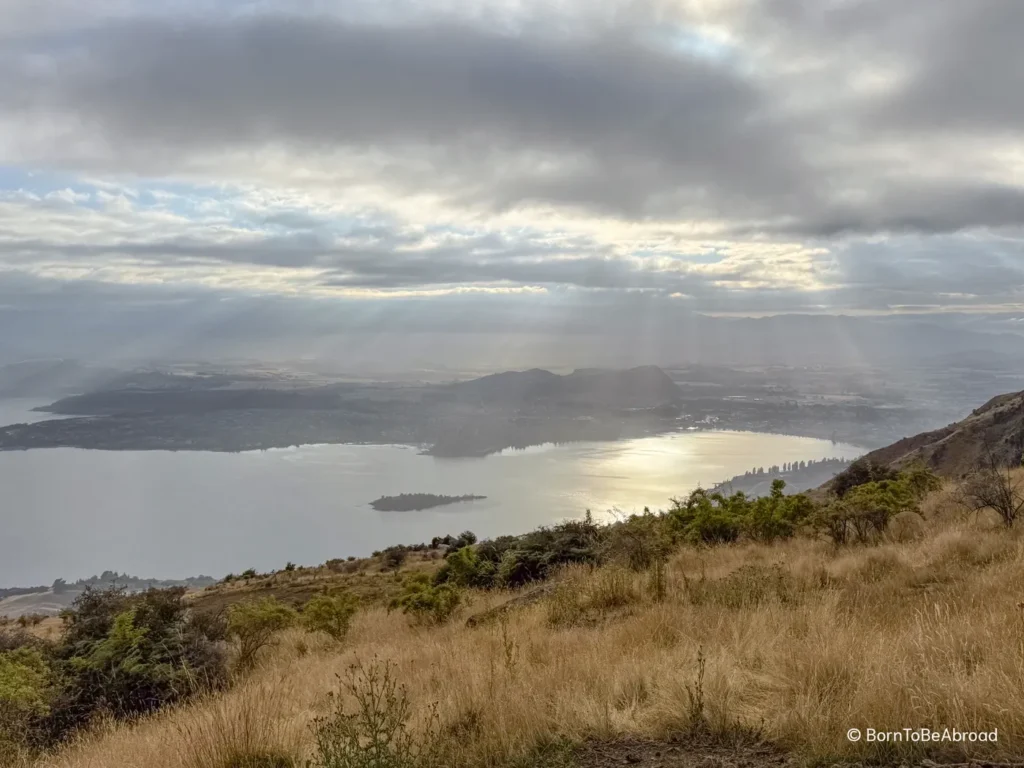 Vue panoramique sur le lac Wanaka avec les montagnes en arrière plan et le soleil qui se reflète sur le lac