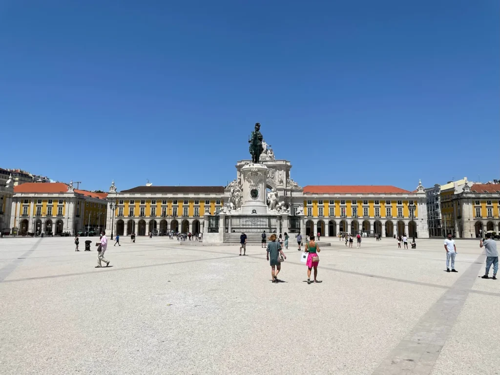 Statue au milieu d'une place avec des bâtiments colorés en fond