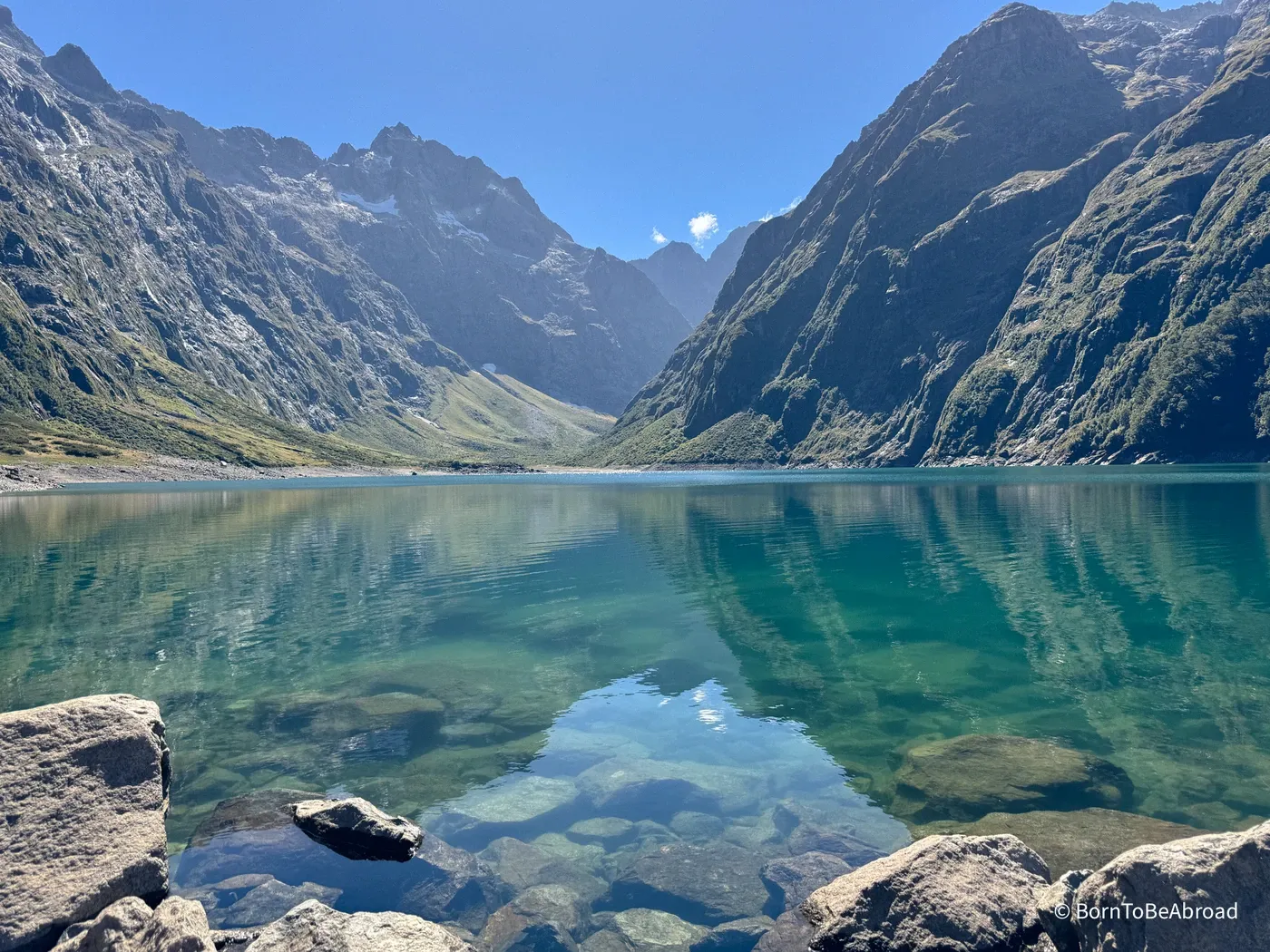 Un lac de couleur turquoise niché au milieu des montagnes sous un temps ensoleillé